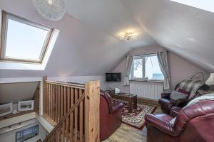 a living room with leather furniture and a staircase at Penrhyn Cottage in Cemaes Bay