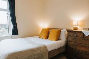 Cette chambre comprend un lit avec des oreillers jaunes et une commode. dans l'établissement 3 Bed - Luxury Peaceful Stay - Preston City Centre, à Preston