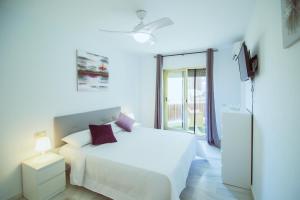 a white bedroom with a bed and a window at Sol & Mar apartment in Fuengirola