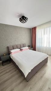 1 dormitorio con 1 cama grande con almohadas rosas en The Sea Escape Apartment, en Constanţa