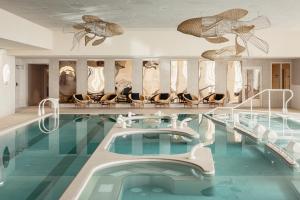 uma piscina num hotel com cadeiras e uma piscina em Emeria Dinard Thalasso Spa - Avril 2024 Réouverture après rénovation em Dinard