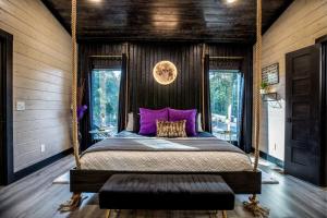 a bedroom with a swing bed with purple pillows at Enchanting Escape for Two in Broken Bow