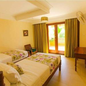 a hotel room with two beds and a desk at Villa Mandhari - Diani Beach in Diani Beach