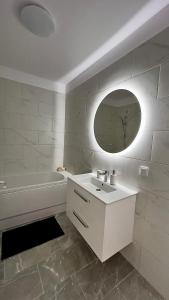 Baño blanco con lavabo y espejo en The Sea Escape Apartment, en Constanţa
