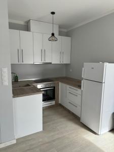 a kitchen with white cabinets and a white refrigerator at XL Apartman in Teslić