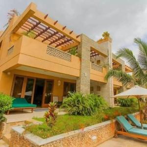 a house with a patio and an umbrella at Villa Mandhari - Diani Beach in Diani Beach