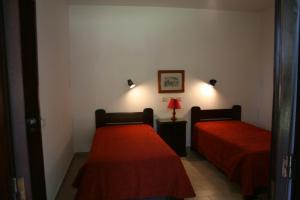 una camera con due letti con lenzuola rosse e una lampada di Aldeia Da Falesia ad Albufeira