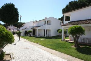 Une rangée de maisons blanches avec des arbres et de l'herbe dans l'établissement Aldeia Da Falesia, à Albufeira