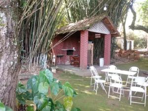 a patio with white chairs and a table and a building at Apartamento no Condomínio Imperial in Lambari