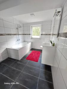 a bathroom with a white tub and a red rug at Hotel am See Radevormwald in Radevormwald