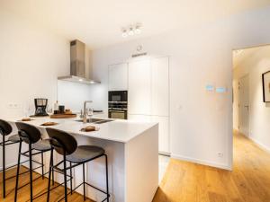una cocina con encimera blanca y taburetes de bar en Jolie appartement haut standing Liège Guillemins en Lieja