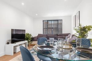 comedor con mesa de cristal y sillas azules en Digbeth Luxury Apartment, en Birmingham