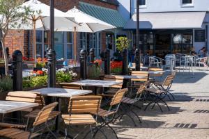 an outdoor cafe with tables and chairs and umbrellas at The BoatShed in Lymington