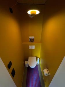 a bathroom with a white toilet and a yellow wall at Adventure Camp Schnitzmühle in Viechtach