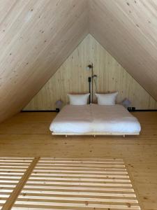 a white bed in a attic with a roof at Adventure Camp Schnitzmühle in Viechtach