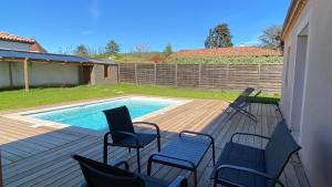 eine Terrasse mit Stühlen und einem Pool in der Unterkunft Villa spacieuse avec piscine privé , Vallée du Lot in Prayssac