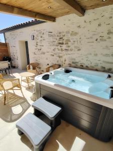 eine große Whirlpool-Badewanne auf einer Terrasse mit Hockern in der Unterkunft La Vie En Gîte (La Grange & Spa) in Sainte-Florence