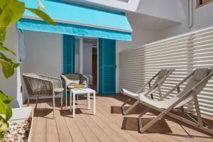 un patio con sillas, mesa y toldo azul en Hotel Colonial en Colonia de Sant Jordi