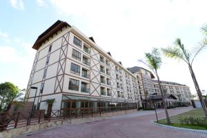 een groot wit gebouw met een palmboom ervoor bij Vista Azul Apart Hotel - Vista Pedra Azul in Domingos Martins