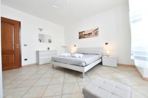 um quarto branco com uma cama e uma cadeira em Il Mosaico Apartment em Oristano