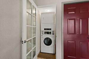 a laundry room with a washing machine and a red door at Red Roof Inn Carson - Wilmington, CA in Wilmington