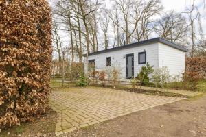 een klein wit huis midden in een tuin bij Gezellig modern chalet midden op de Veluwe in Epe