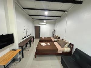 um quarto com 2 camas, uma secretária e uma televisão em BIG BEN Residence em Kaeng Khoi