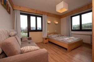 a living room with a bed and a couch at Pod Hawraniem pokoje z widokiem na Tatry Ski & Bike Friendly Jurgów in Jurgów