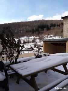 Bol d'air à Mijanès في Mijanès: طاولة نزهة مغطاة بالثلج بجوار مبنى