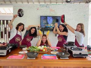a group of women in a kitchen with their hands in the air at Anggrek Putih Homestay & Cooking Class in Senggigi 