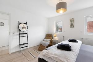 a white bedroom with a bed and a chair at Ferienwohnung Mittenglück in Unterlenningen