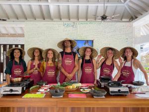 a group of people wearing straw hats standing in front of a table at Anggrek Putih Homestay & Cooking Class in Senggigi