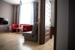 sala de estar con silla y sillas rojas en ADLER Bed&Breakfast, en Łódź