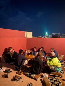 a group of people sitting around a red wall at Olympe Surf & Yoga in Tamraght Ouzdar