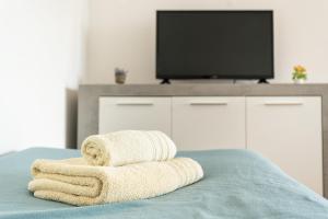 two towels sitting on top of a bed with a tv at BLife Bandaya private apartment in Faro