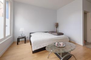 ein weißes Schlafzimmer mit einem Bett und einem Tisch in der Unterkunft L'Escale Clermontoise - studio 26m2 in Clermont-Ferrand