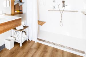 baño con ducha y suelo de madera. en Microtel Inn & Suites Springville, en Springville