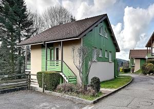 a green and white house on the side of a street at Les Chênes Rouges - Appt avec piscine partagée in Gérardmer