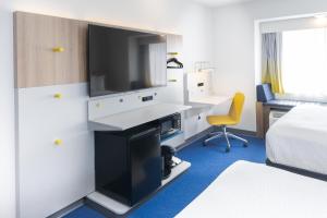 Habitación de hotel con cama y escritorio con TV. en Microtel Inn & Suites Springville, en Springville