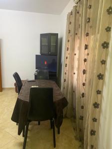 uma mesa com cadeiras e uma televisão num quarto em Henri Apartaments em Durrës