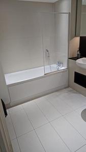 a white bathroom with a tub and a sink at Greenwich Glamorous 2-Bed Apartment in London