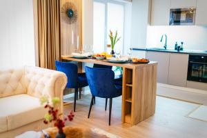a kitchen with a table and blue chairs in a room at Prestige ApartHotel Brasov in Braşov
