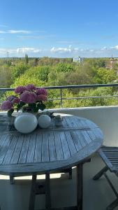 een houten tafel met een vaas met bloemen op een balkon bij Kleine zimmer in luxus wohnung in Schenefeld
