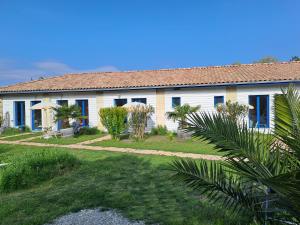 a white house with blue windows and a yard at La Cadournaise in Saint-Seurin-de-Cadourne