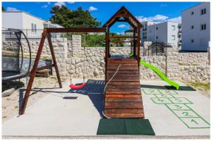 a playground with a wooden swing set in a park at M&Z Apartmani in Primošten