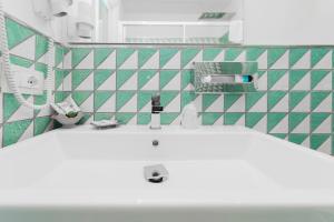 La salle de bains est pourvue d'un lavabo blanc et de carrelage vert et blanc. dans l'établissement Hotel Miramare, à Maiori