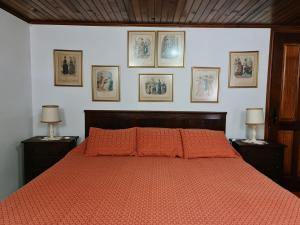- une chambre dotée d'un lit avec des draps orange et des photos murales dans l'établissement Quinta da Mochada, 
