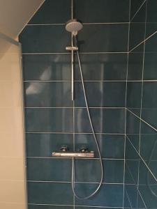 a shower with a hose on a blue tiled wall at A 2’ du port & du bourg maison spacieuse in La Trinité-sur-Mer