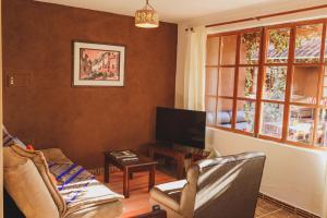 a living room with a couch and a tv at Kutimuy Lodge in Urubamba