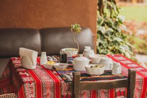 a table with a red table cloth with bowls and cups at Kutimuy Lodge in Urubamba